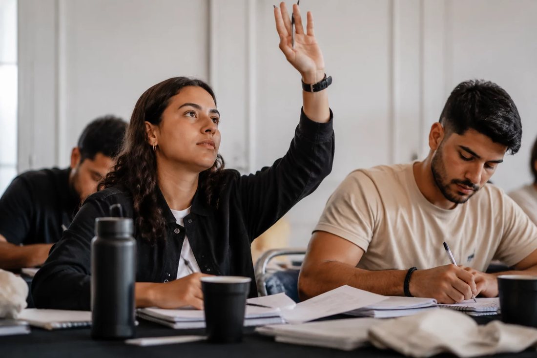 Facilitador de pé apontando para um argumento escrito no quadro durante a sessão
